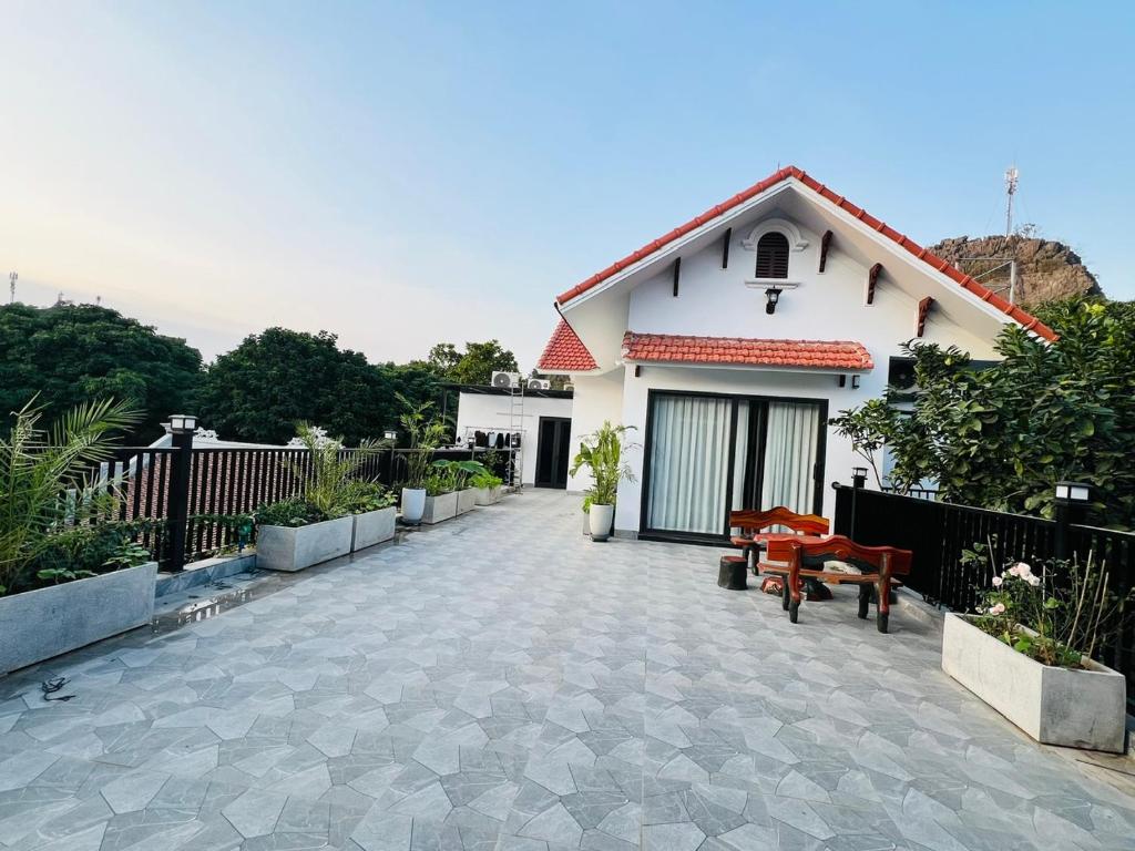 a white house with a patio and a fence at Tịnh Garden Homestay in Yên Ha
