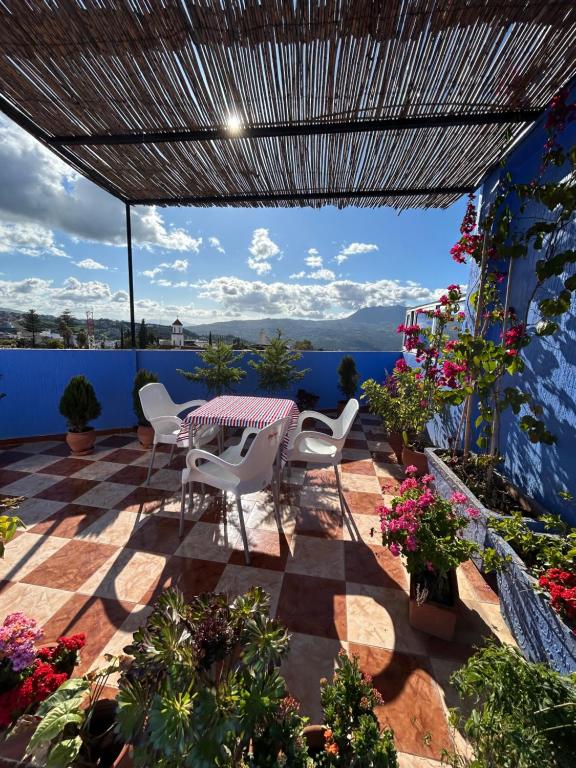 un patio con tavolo, sedie e fiori di Hotel Al Manar a Chefchaouen