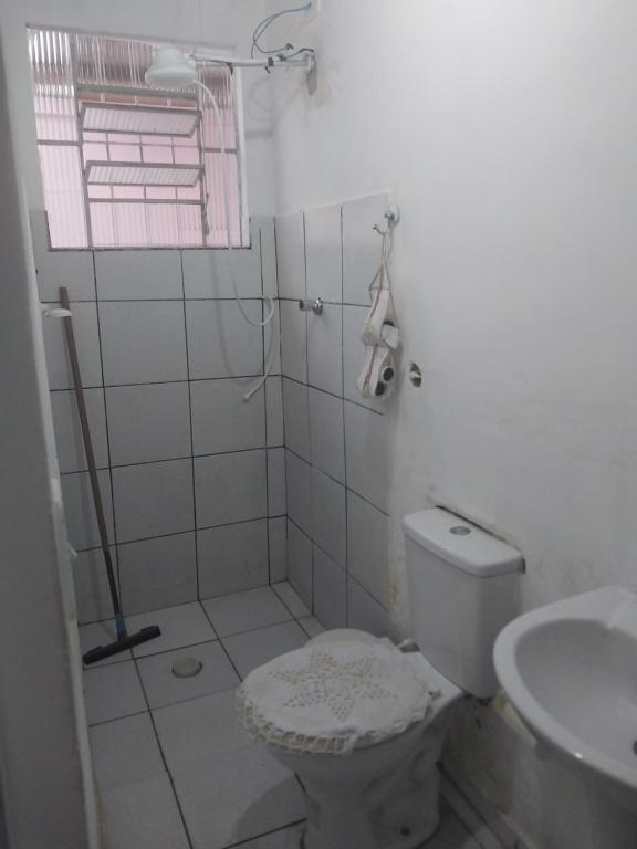 a white bathroom with a toilet and a sink at Aluga se quarto para o Carnaval in Caraguatatuba