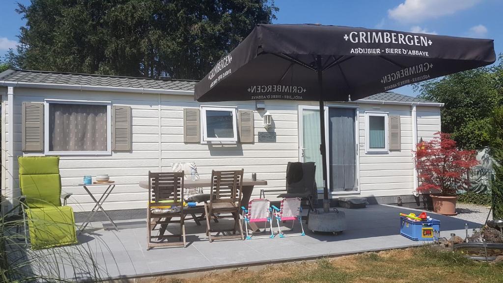 a patio with a table and chairs and an umbrella at Logement vacances Yvoir avec piscine et deux chambres in Yvoir