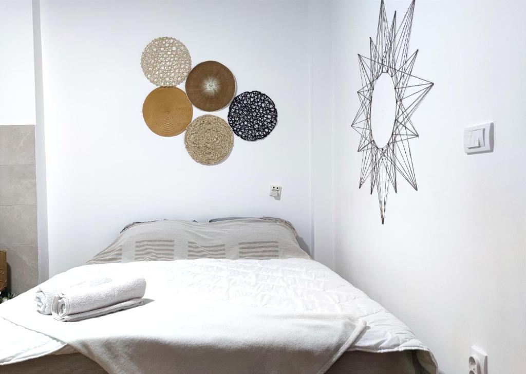 Un dormitorio blanco con una cama y decoraciones en la pared. en Boho-Style Apartment in the city center, en Belgrado