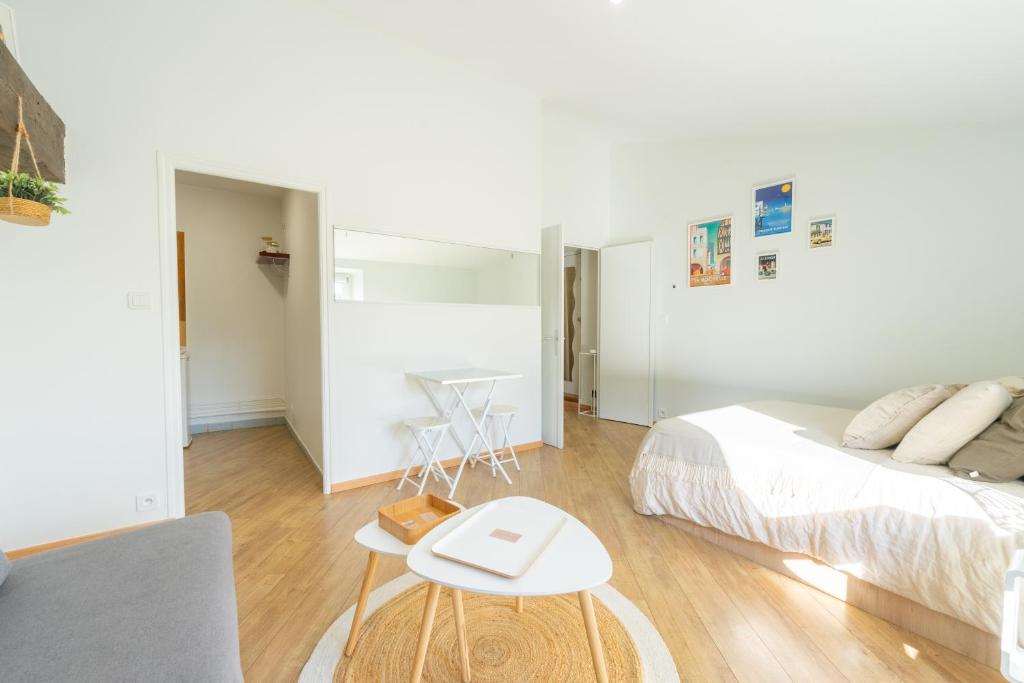 une chambre blanche avec un lit et une table dans l'établissement Appartement lumineux & calme en centre ville, à La Rochelle