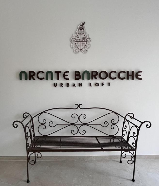 a bench in front of a wall with a sign at Arcate Barocche - Urban Lofts - Scicli in Scicli