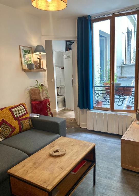 un salon avec un canapé, une table et une fenêtre dans l'établissement Appartement Calme 2 pieces, à Paris