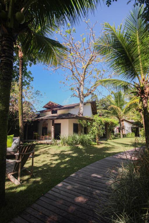 a house with palm trees and a brick walkway at Pousada Quinta de Caraíva in Porto Seguro