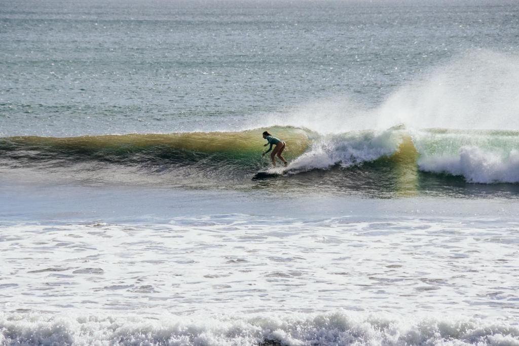 a man riding a wave on a surfboard in the ocean at Nimbu Beachhouse in Transito