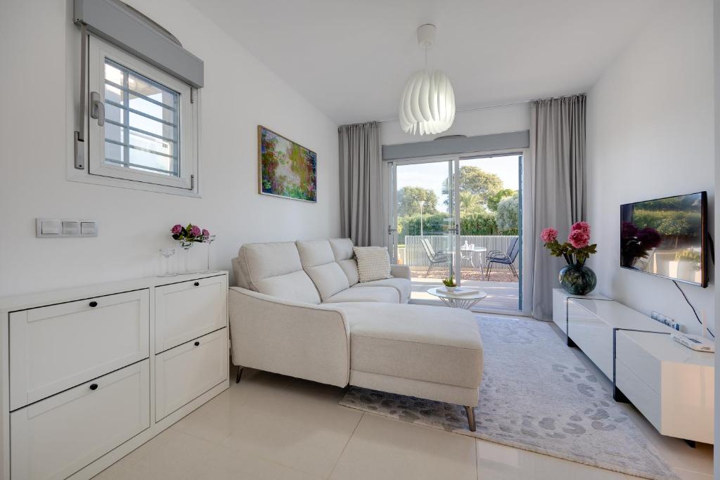 a white living room with a couch and a table at Punta Prima 2 bed apartment with private garden in Punta Prima