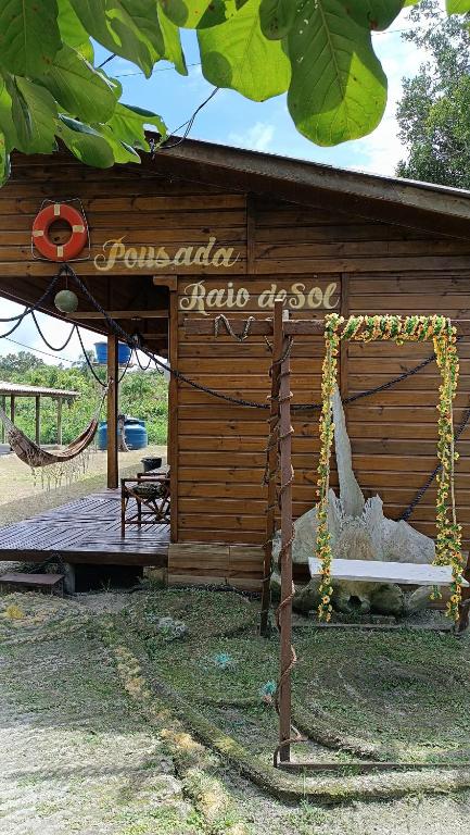 a wooden shed with a sign and a hammock at Pousada Raio de Sol - SUPERAGUI - PR in Superagui