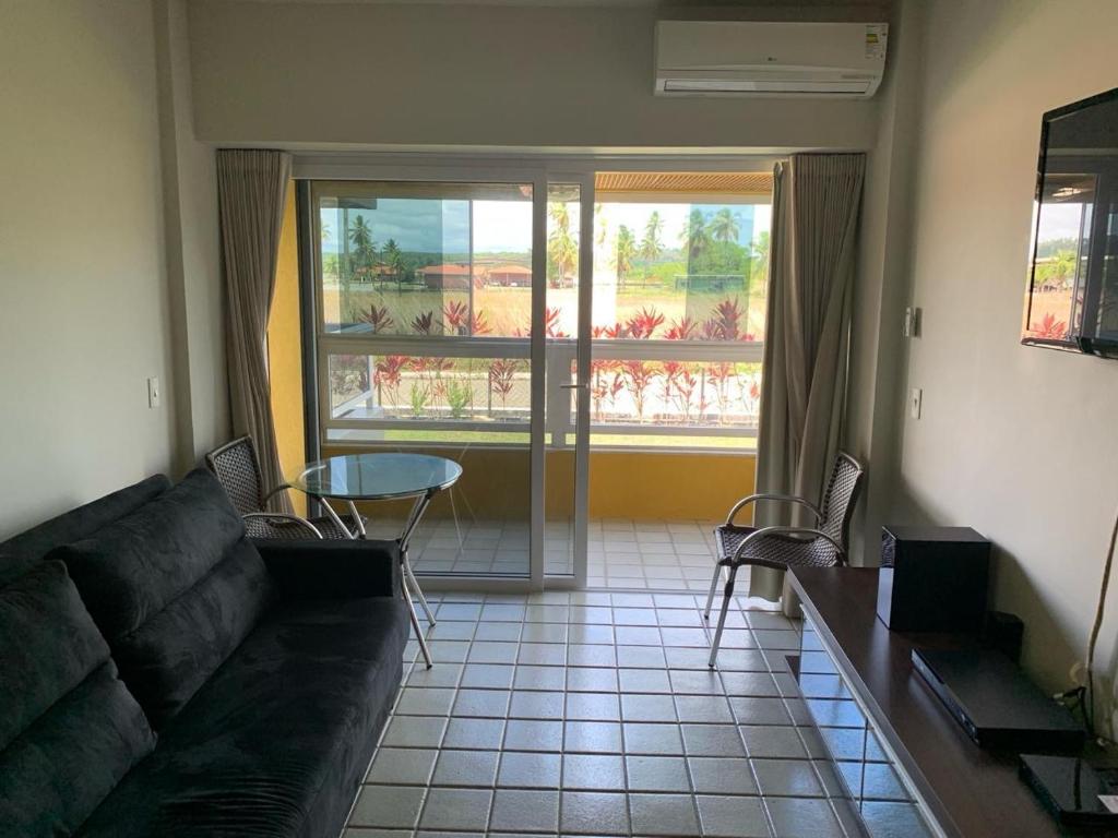 un soggiorno con un divano, un tavolo e una finestra di Gavoa Resort Flat 108 E a Igarassu