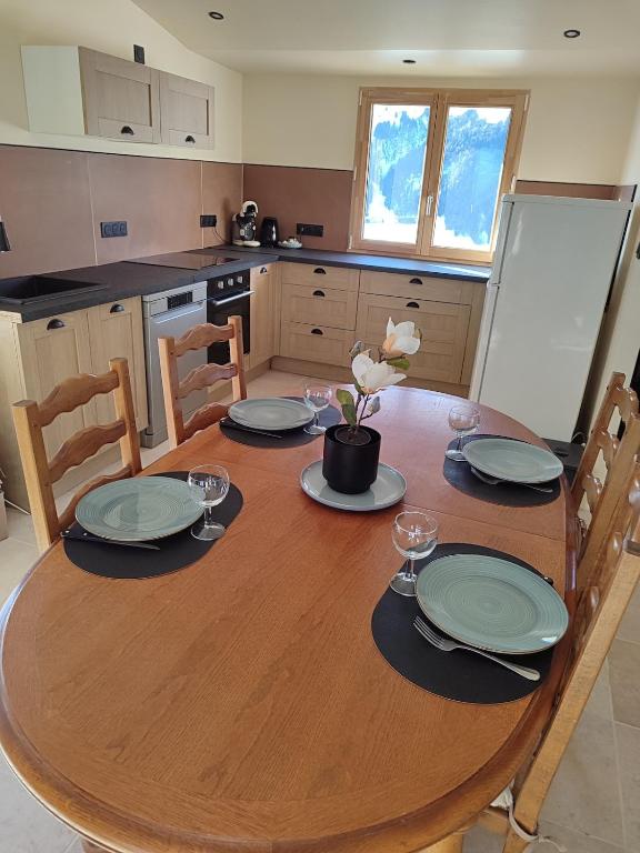 - une table en bois avec des assiettes et des verres dans la cuisine dans l'établissement Gîte Le Polonate, aux Contamines-Montjoie
