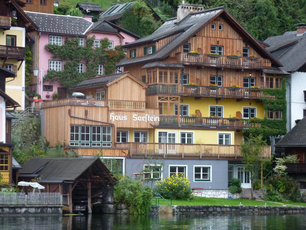 un grande edificio in legno accanto a un corpo d'acqua di Pension Sarstein a Hallstatt
