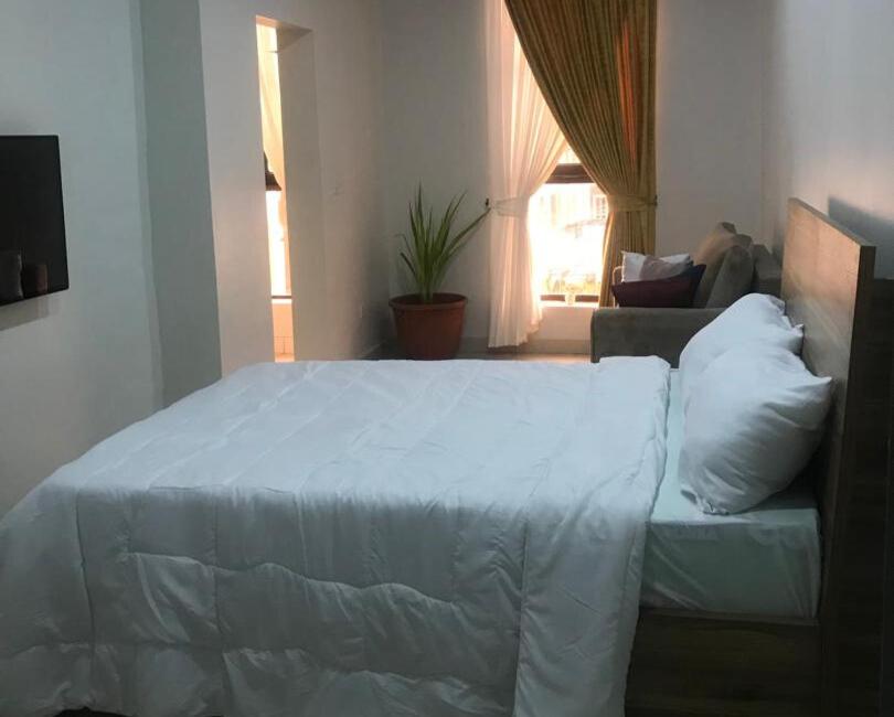 a bedroom with a white bed and a couch at Alfredo Suites-Lekki in Lekki