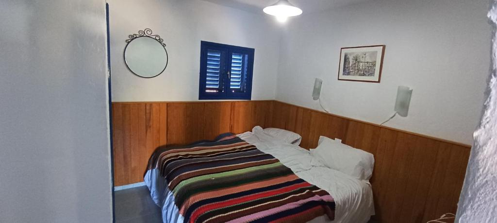 Un dormitorio con una cama con una manta a rayas. en Montaña Las Tortolas, en San Bartolomé