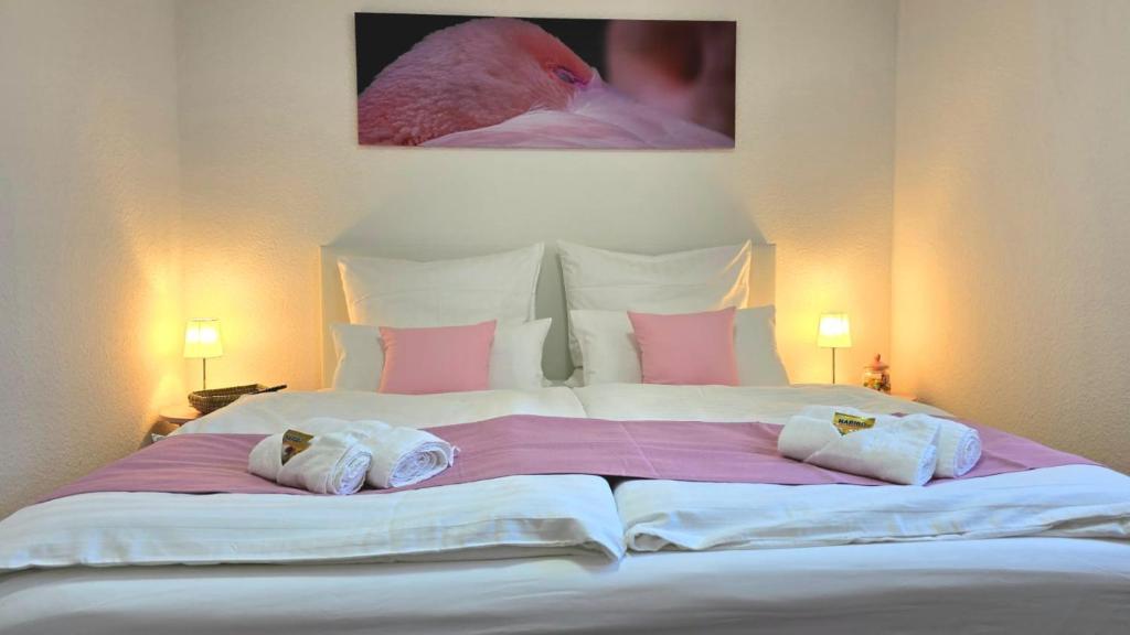 un grande letto bianco con due asciugamani sopra di HAPPY HOMES PINK - Up to 5 - Küche - W-LAN - Netflix - Honig - Badewanne a Nidda