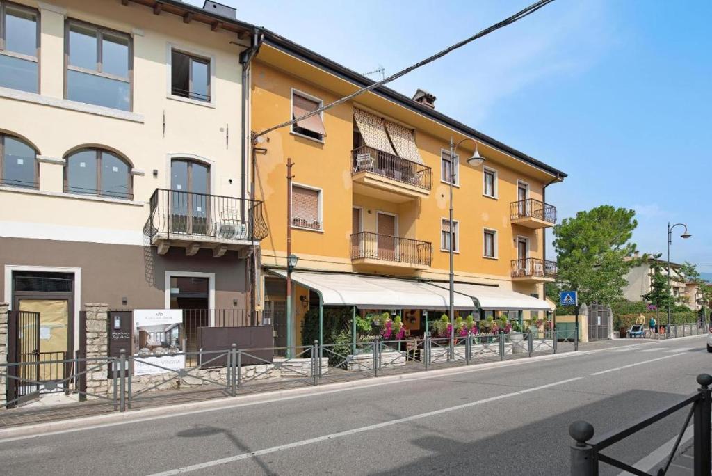 un edificio amarillo al costado de una calle en Achilla 2 appartamenti, en Torri del Benaco