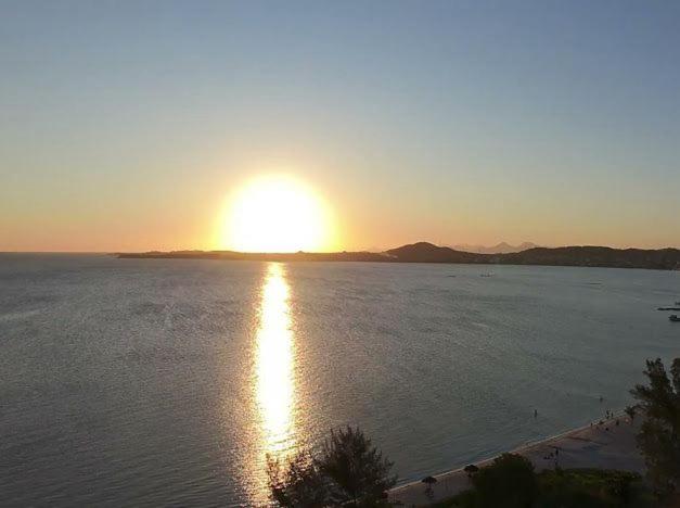 a sun setting over a body of water with a beach at Família Feliz in São Pedro da Aldeia