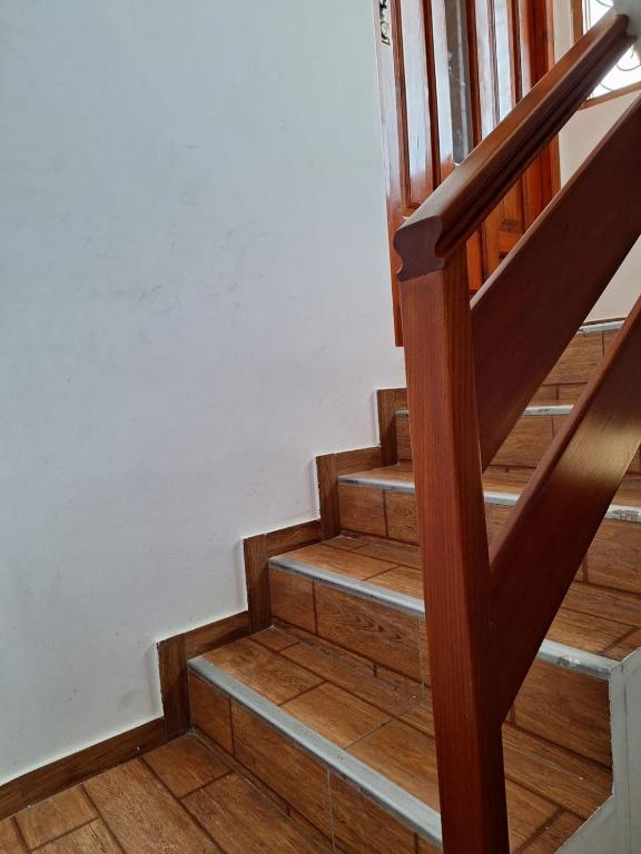 a stairwell with wooden stairs and white walls at Departamento el Mirador Concax in Los Baños del Inca