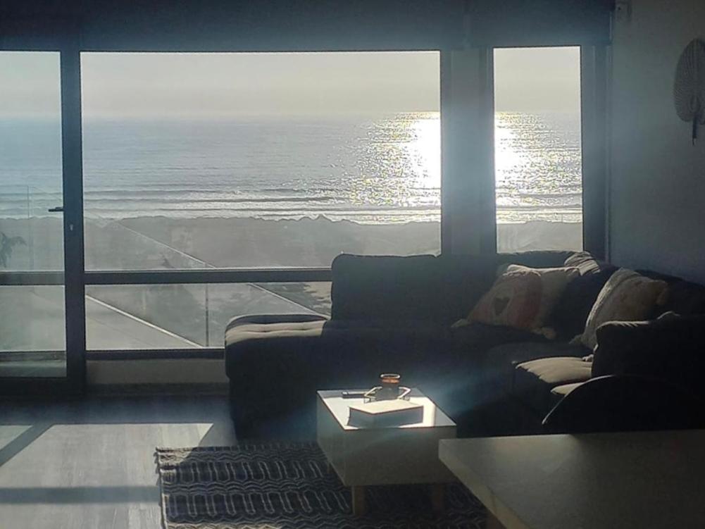 a living room with a couch and a large window at Pingel Home Vista Mar in Valparaíso