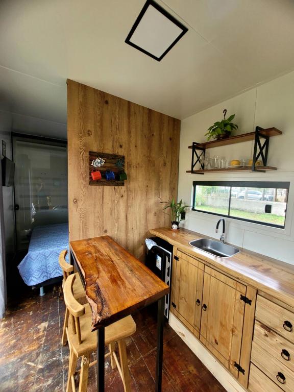 a kitchen with a table and a sink and a bed at POUSADAGiraGarden Containers in Arroio do Silva