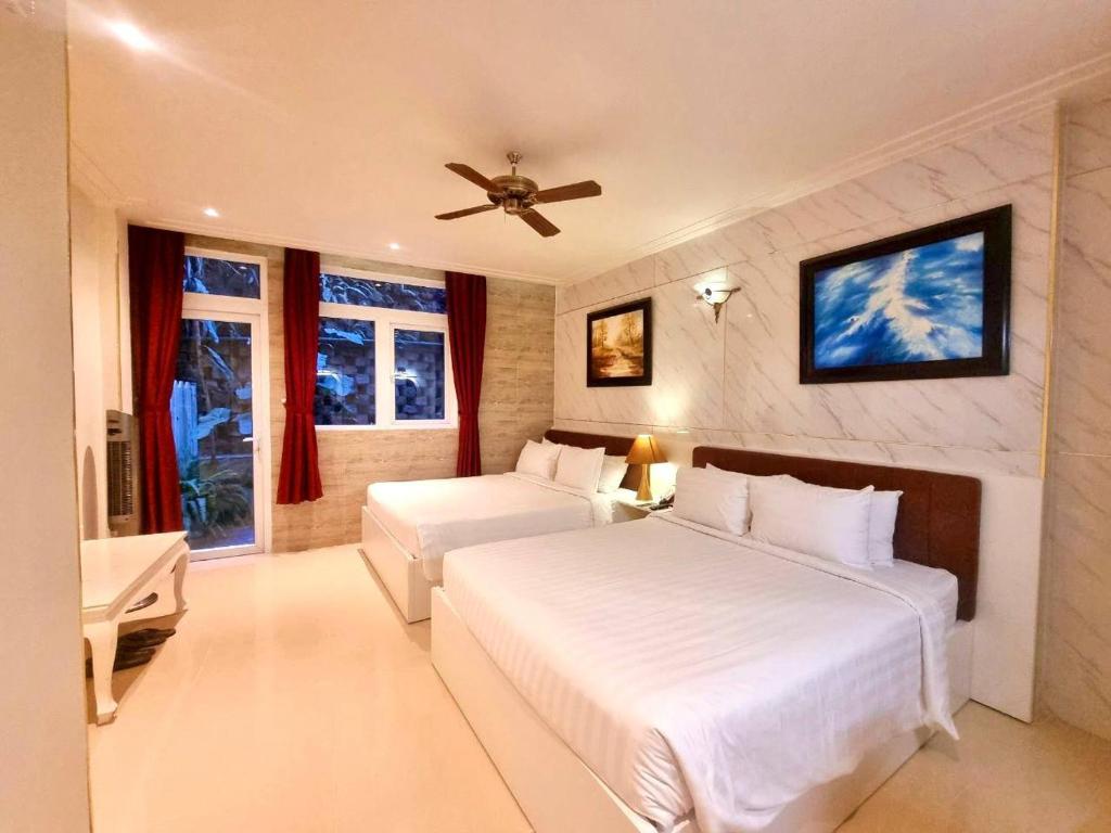 a bedroom with two beds and a ceiling fan at Tulip Hotel 3 in Da Lat