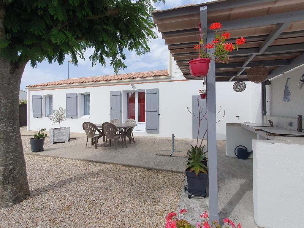 un patio avec une table et des chaises devant une maison dans l'établissement Villa moderne 6 pers. proche plage, jardin, barbecue - FR-1-476-36, à La Faute-sur-Mer