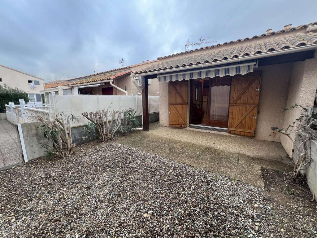 une maison avec un garage doté de deux portes en bois dans l'établissement Pavillon cosy avec terrasse et parking pour 4 personnes - FR-1-701-87, à Valras-Plage