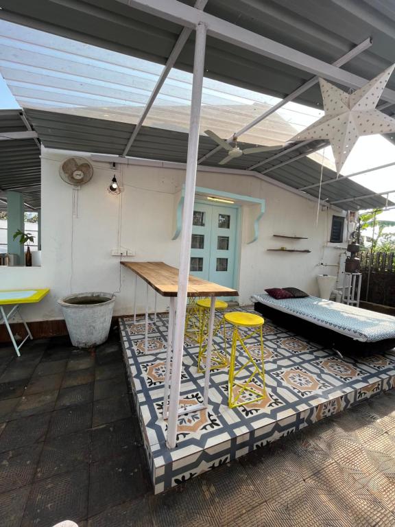 eine Terrasse mit einem Tisch und Stühlen auf einem Teppich in der Unterkunft Ohana by your barn in Goa