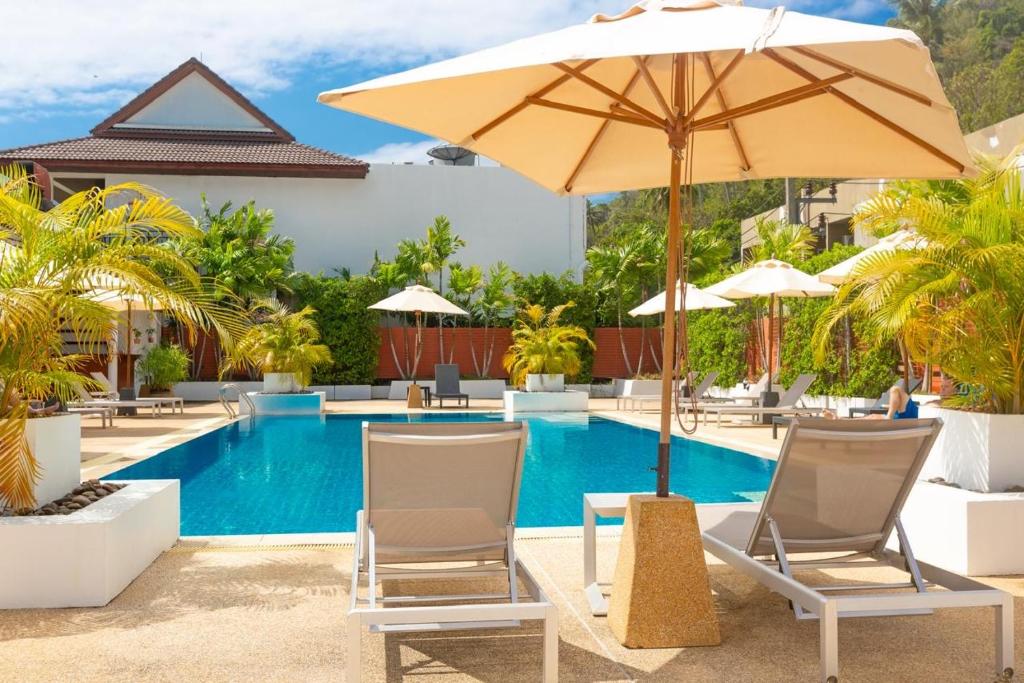una piscina con sillas, una sombrilla y una piscina en Naiharn beach sands Apartment, en Nai Harn Beach