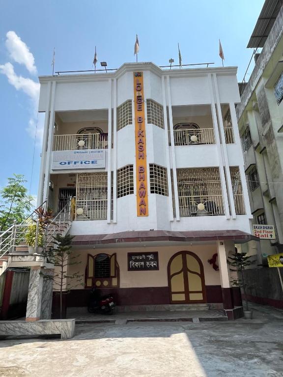 a white building with a balcony on top of it at Lodge Bikash in Siliguri