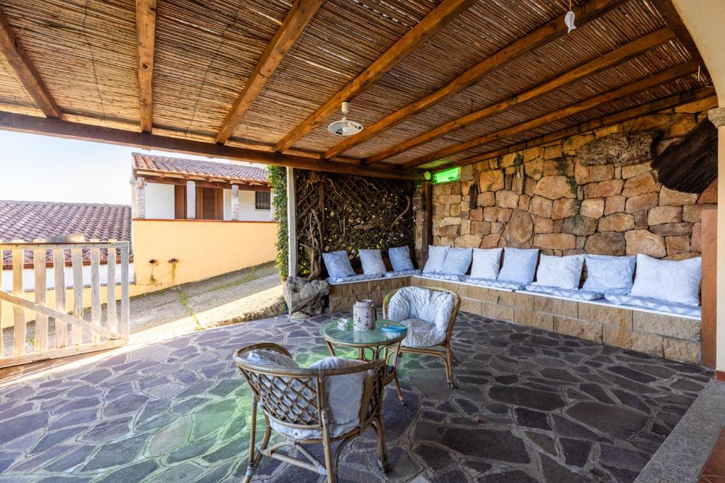 patio ze stołem i krzesłami oraz kamienną ścianą w obiekcie Lulamax Sardegna w mieście Budoni