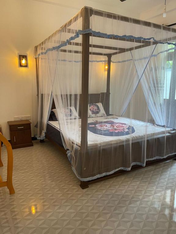 a bedroom with a canopy bed with mosquito nets at Garden Villa in Kumbalgama