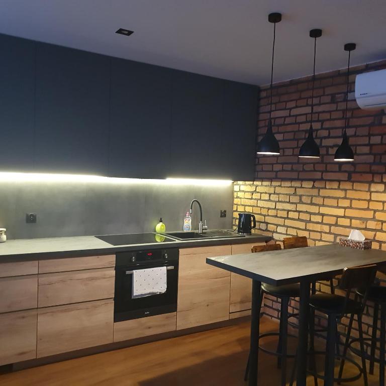 a kitchen with black cabinets and a table with a sink at Kościuszki in Sanok