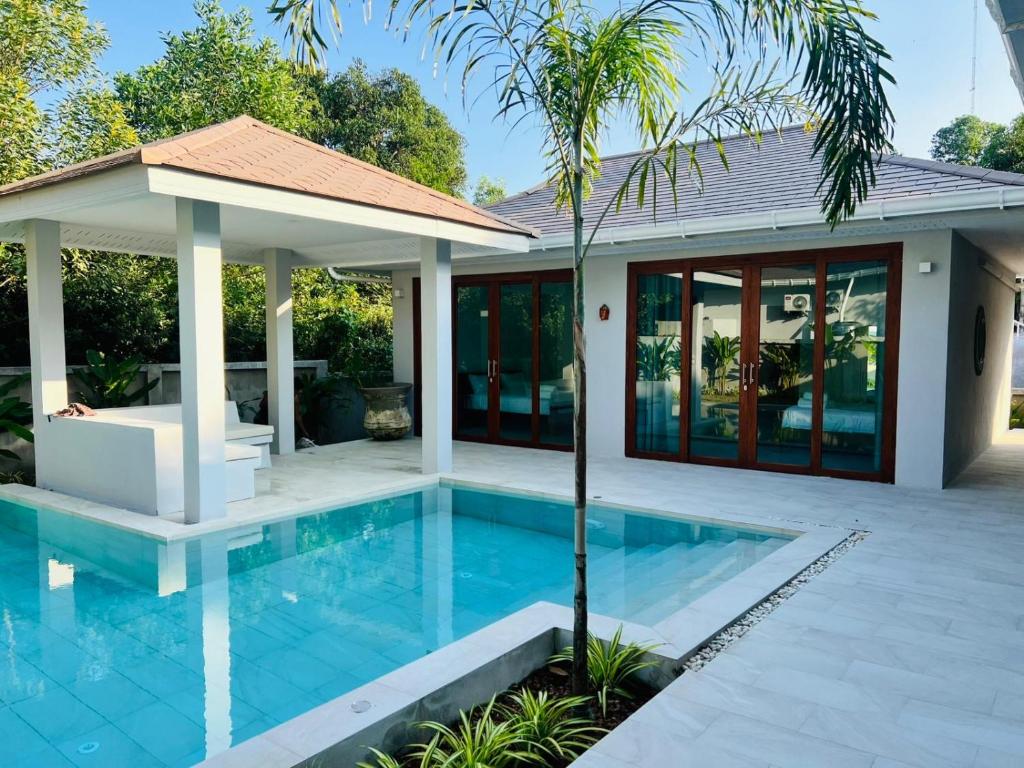 a villa with a swimming pool in front of a house at Villa The Palm Sip Song in Koh Phangan