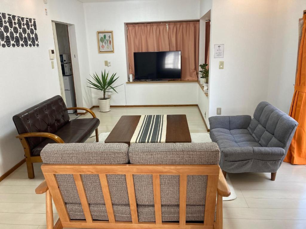 a living room with a couch and a table at Narita Traveler's Guest House 成田 トラベラーズ ゲストハウス in Tomisato