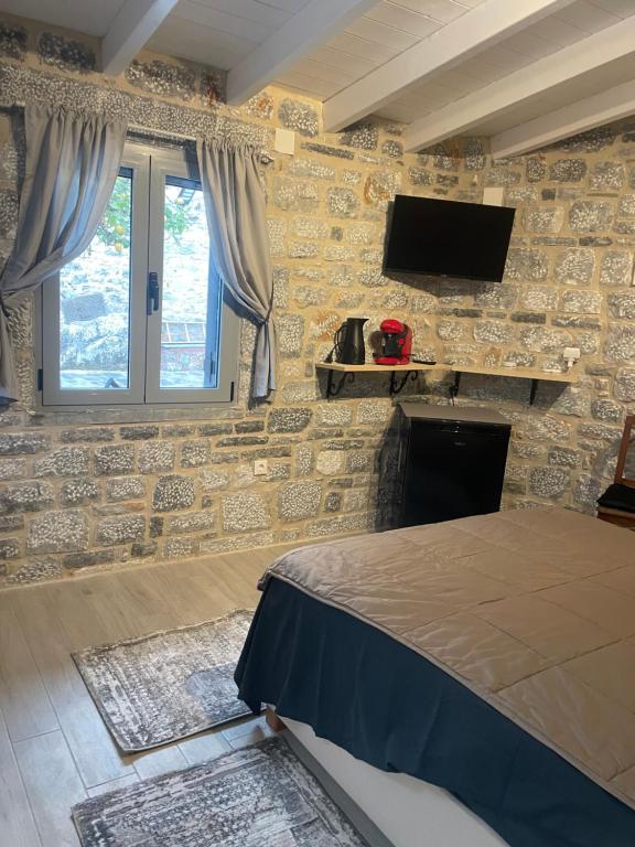 sypialnia z kamienną ścianą z łóżkiem i telewizorem w obiekcie Aroma Avlis Apartments w mieście Areopolis