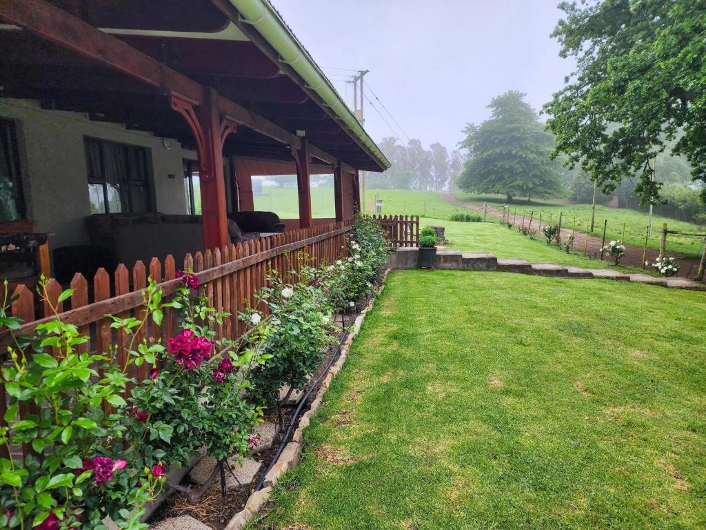 a house with a fence and flowers next to a yard at Hogsback Misty Oaks Cottage in Hogsback