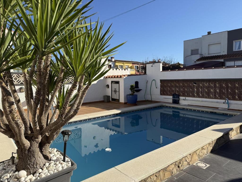 a swimming pool with a palm tree next to a building at AwayDays - Casa con Piscina in Empuriabrava