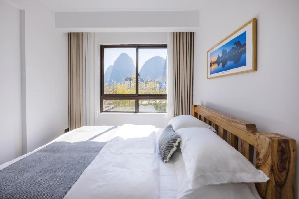 a bedroom with a bed with a large window at Phoenix Tree Lodge in Fuli