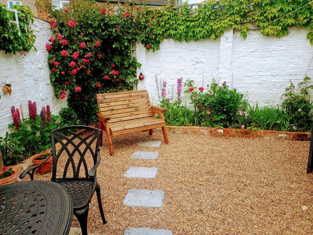 a bench and a chair in a garden with roses at Pankhurst, Louth in Louth