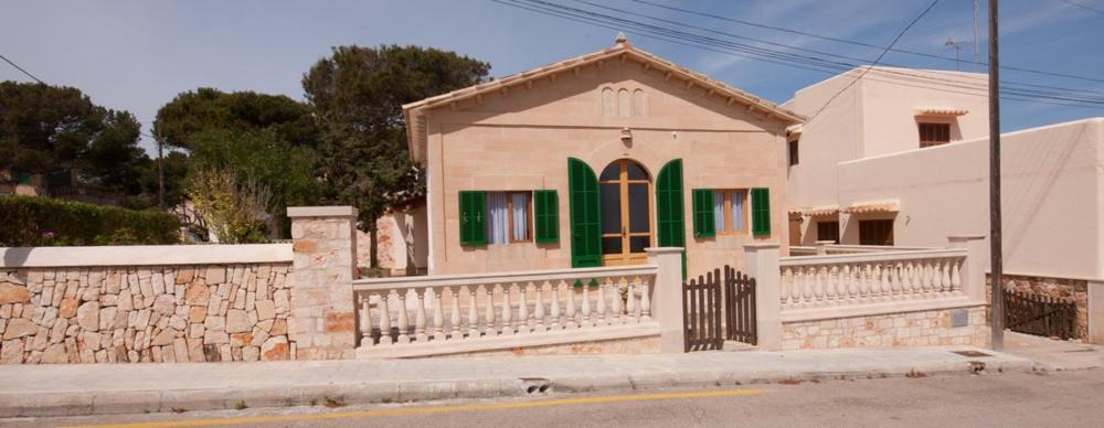 a white house with green doors and a fence at Casa Maremar in Cala Figuera