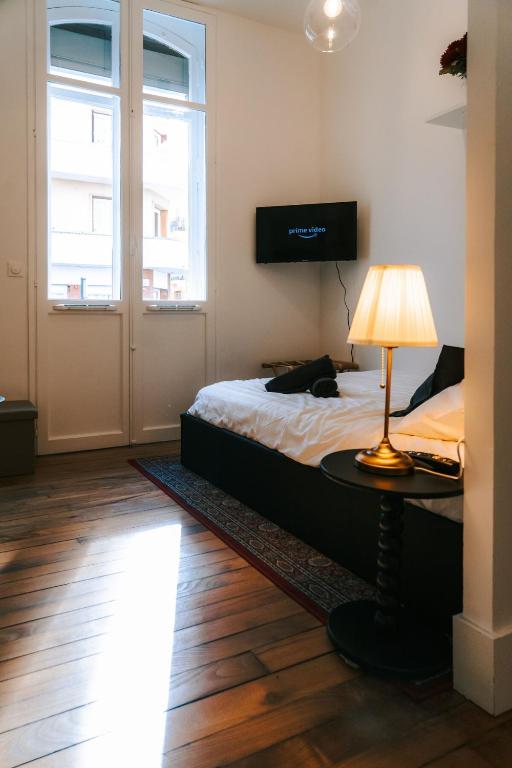 une chambre avec un lit et une table avec une lampe dans l'établissement L 'Haussmannien - Chic - Gare - Metro - Centre, à Toulouse