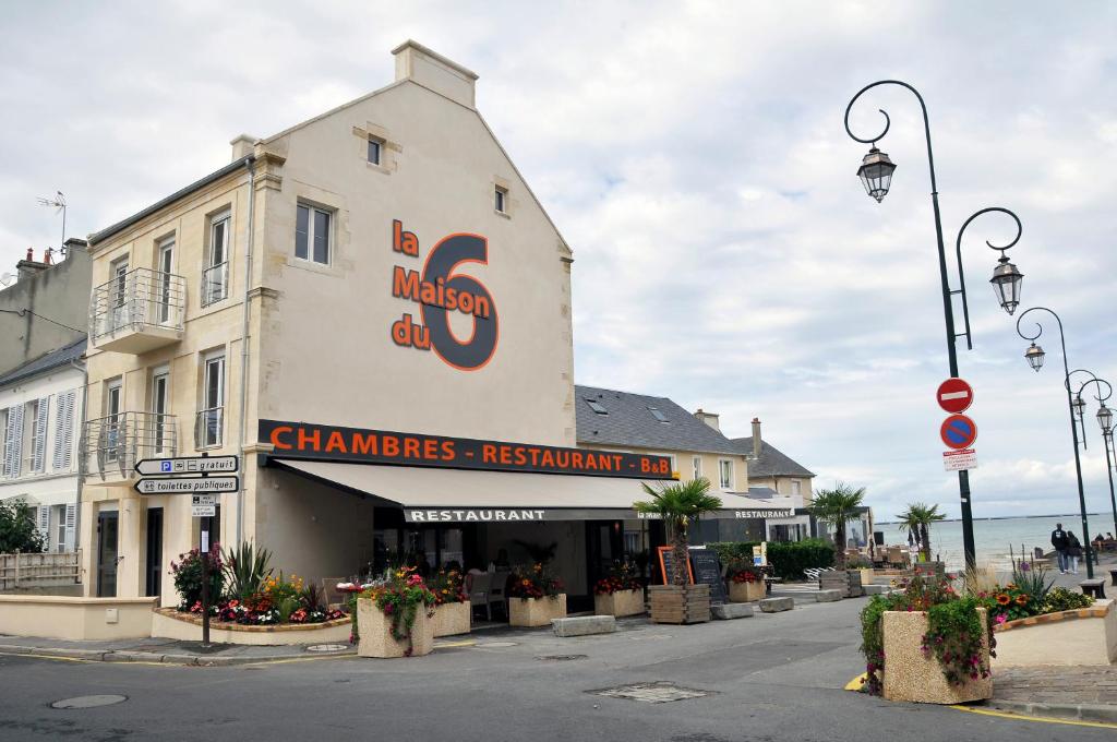 un edificio con un cartello sul lato di una strada di La Maison Du 6 ad Arromanches-les-Bains