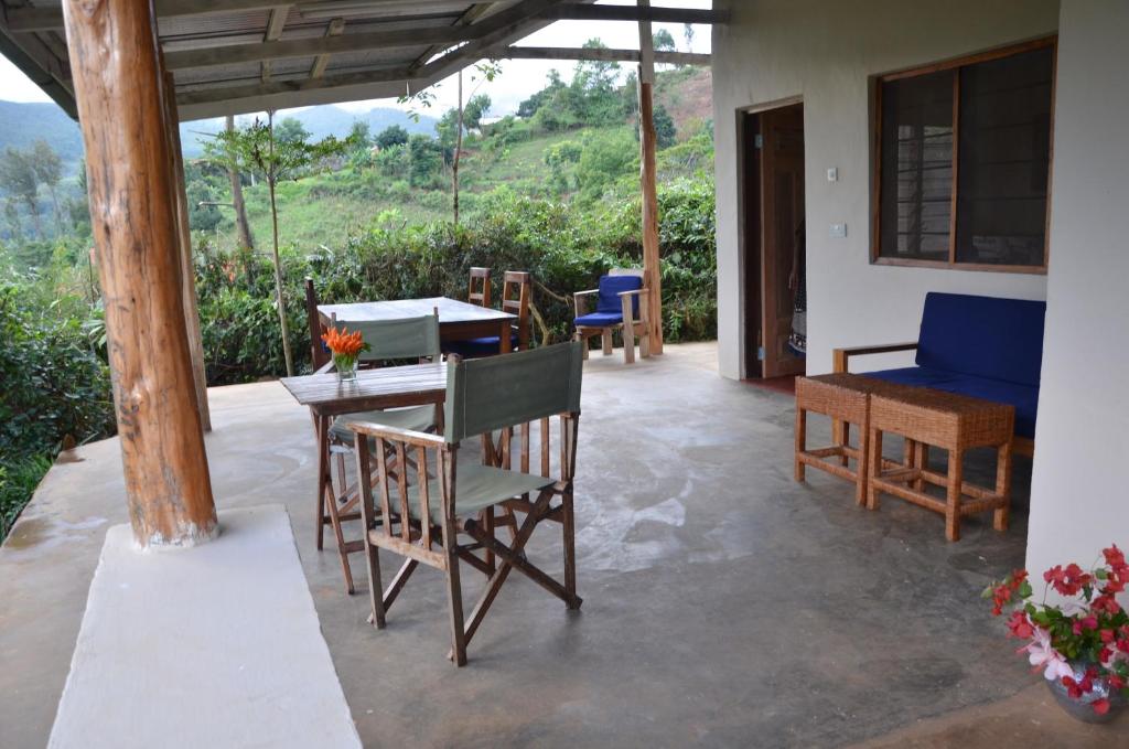 eine Terrasse mit Stühlen und einem Tisch mit Blick auf einen Hügel in der Unterkunft Milemeleni Guesthouse in Lushoto