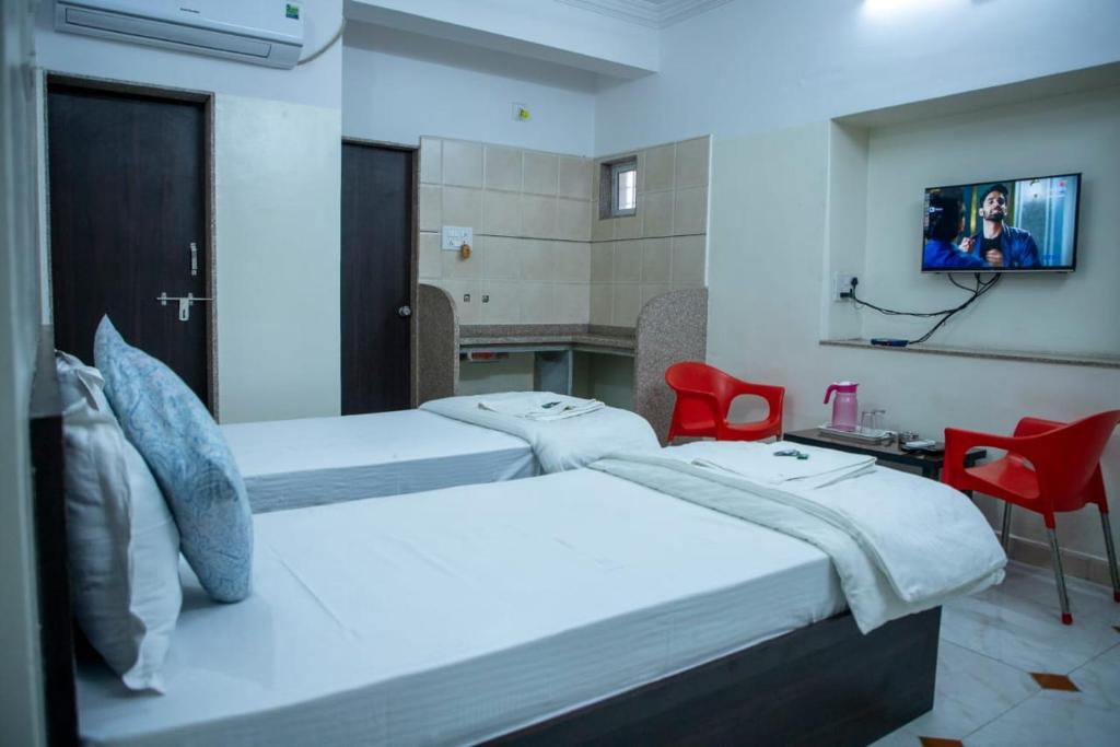甘德希罕Hotel Aditya Inn的一间有两张床和一台电视的酒店房间