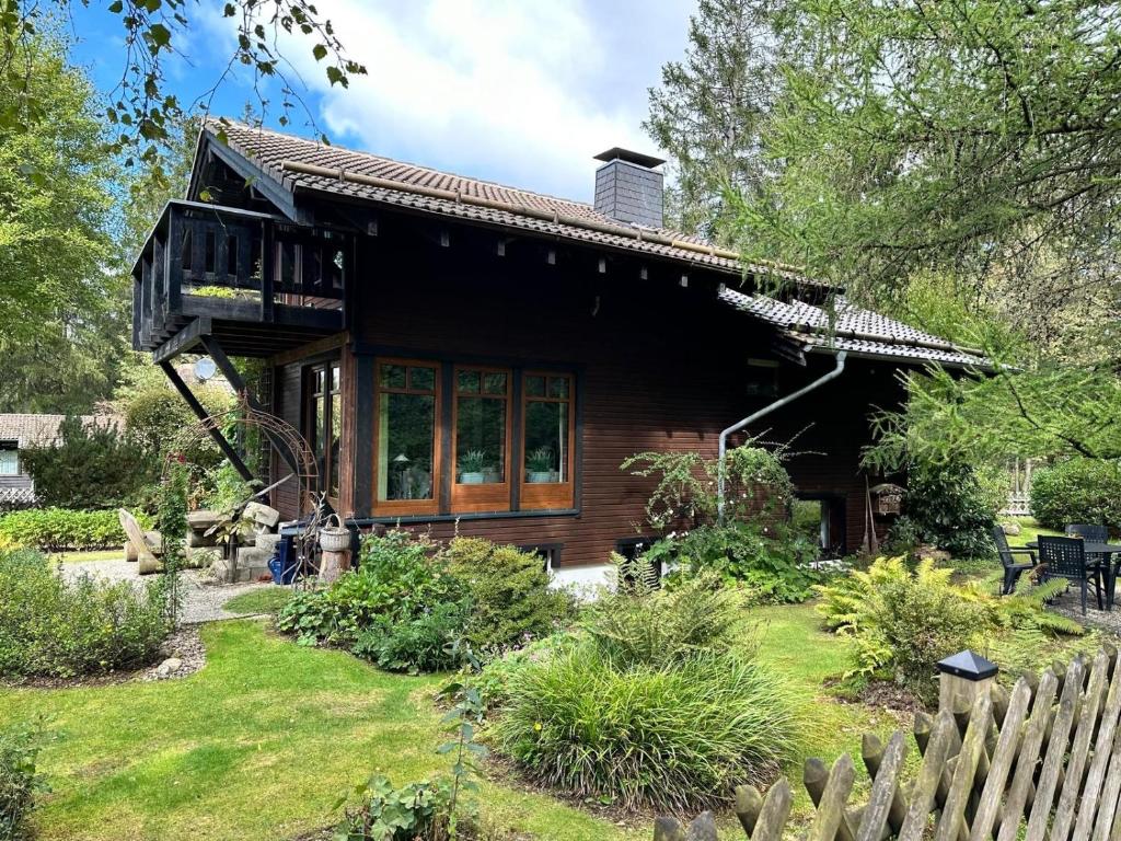 een houten huis met een balkon en een tuin bij Waldzauber am See in Clausthal-Zellerfeld