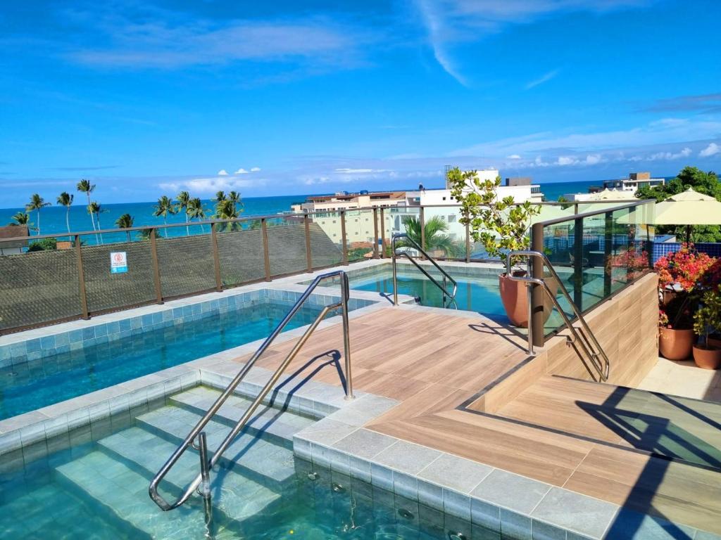 a swimming pool with a view of the ocean at Porto BLUE 05 térreo Centro de Porto de Galinhas in Porto De Galinhas