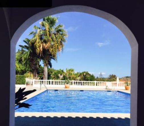an archway leading to a swimming pool with a palm tree at Vila Van Gogh in Luz