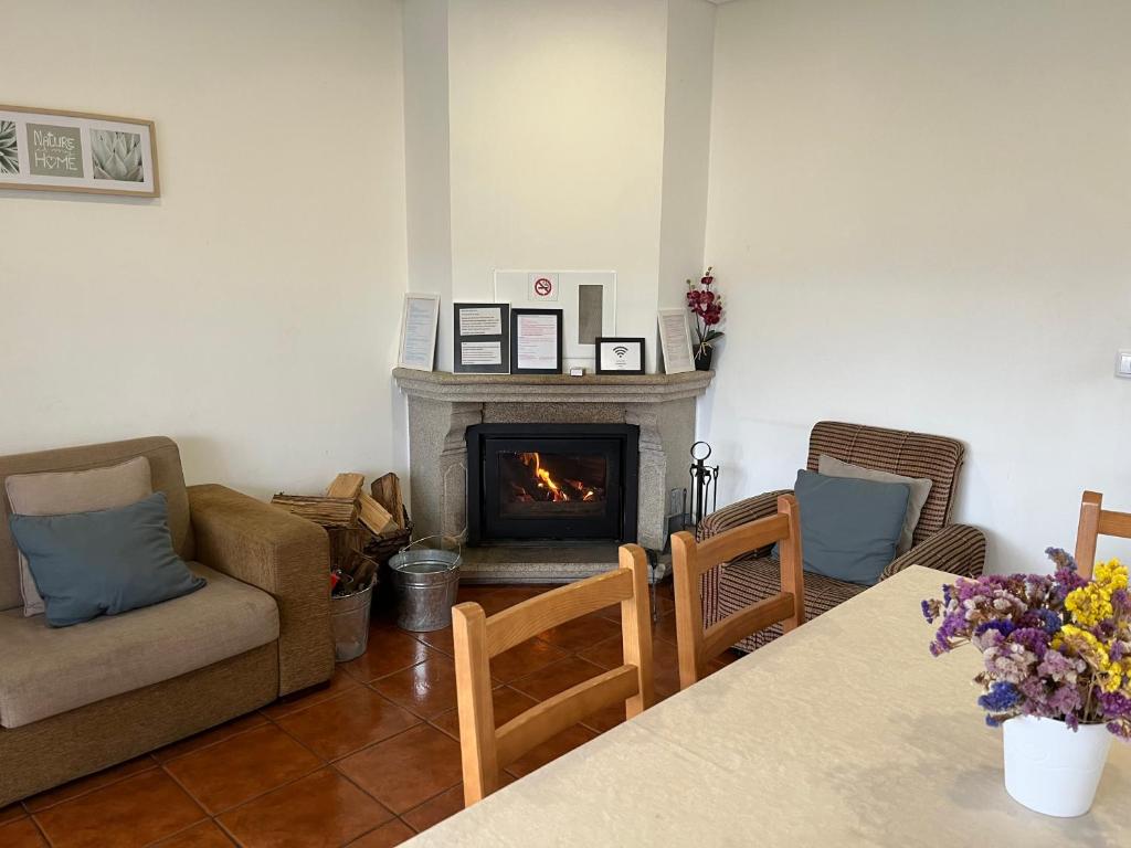 a living room with a fireplace and a table and chairs at Casa de Casarelhos - Andar de Moradia - Lareira - Vistas - Gerês in Geres