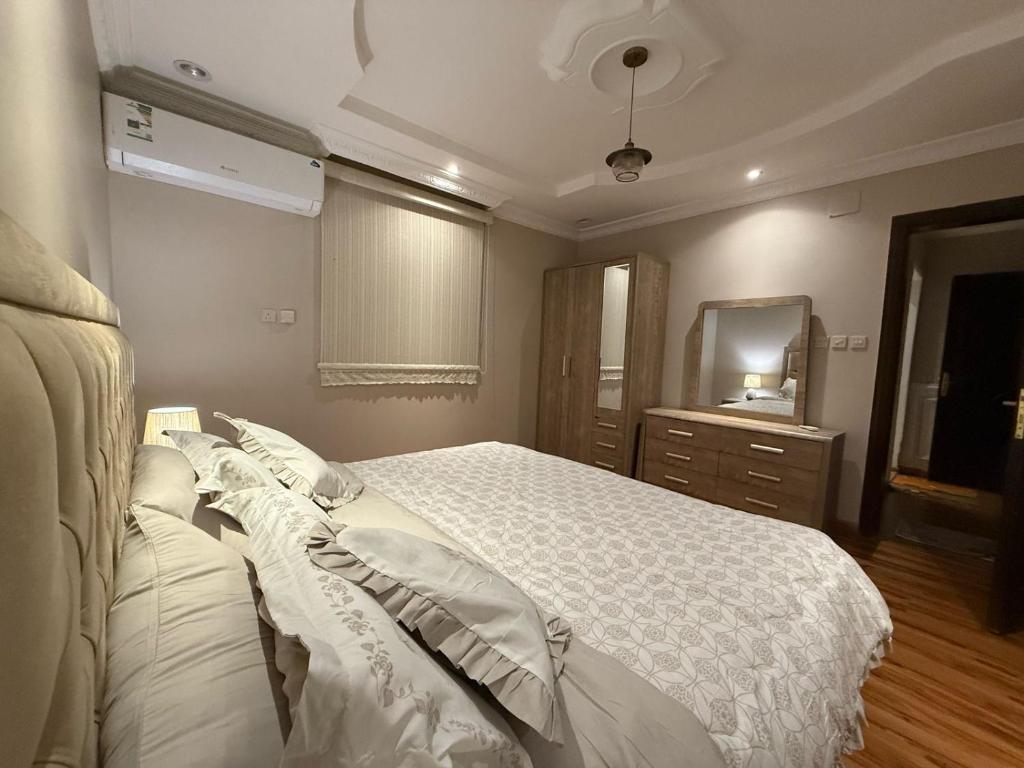 a bedroom with a white bed and a mirror at نزل العقيق بحي الجامعة in Medina