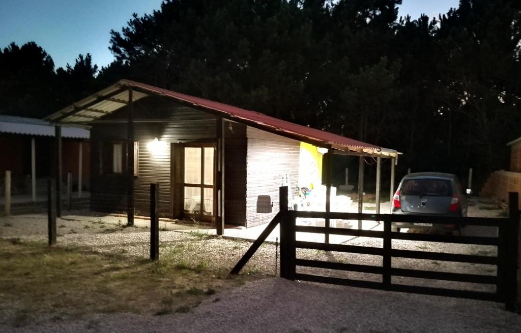 a smallshed with a car parked next to a fence at Cabaña Faro di luce in Santa Vitória do Palmar